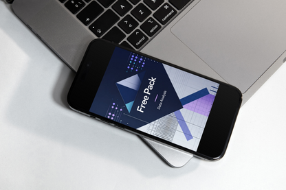 A smartphone lying on a white surface next to an open silver laptop, displaying a digital design asset preview titled 'Free Pack' with geometric graphics.